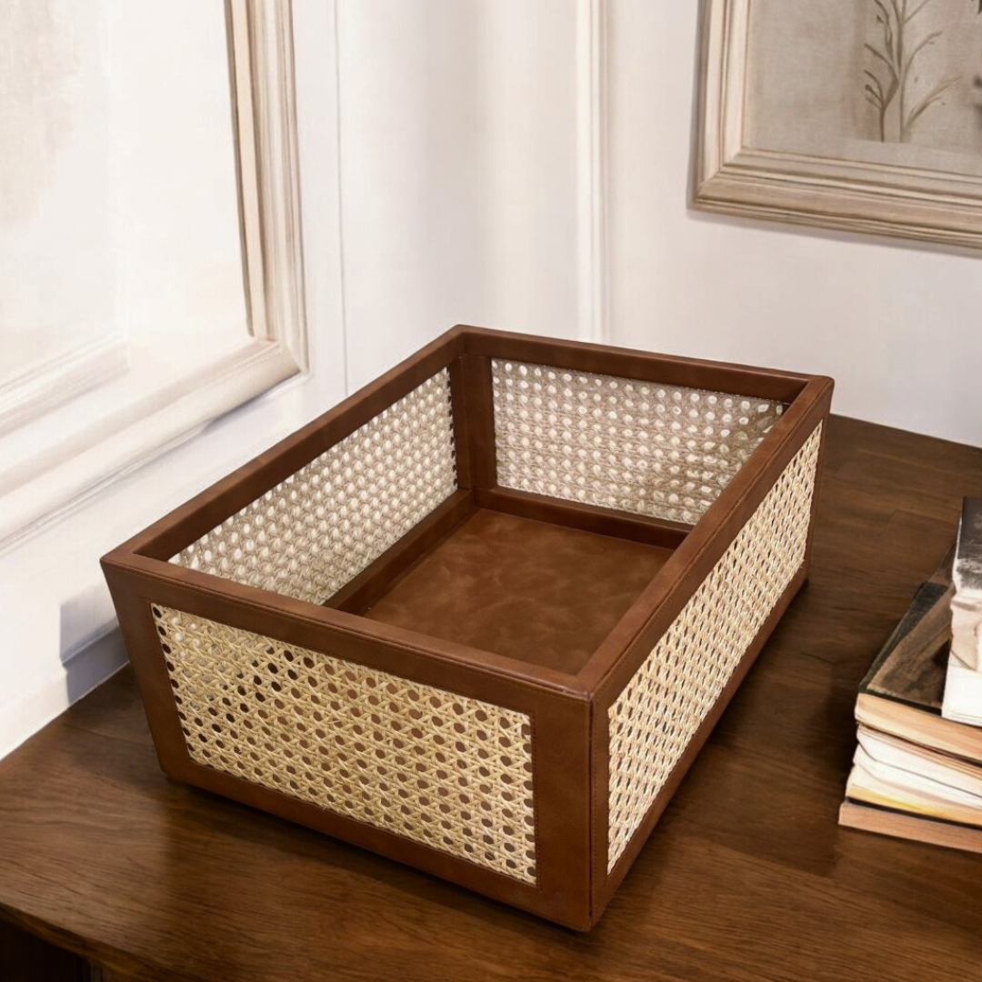 A rectangular brown rattan basket organiser with a vegan leather trim, placed on a wooden surface.